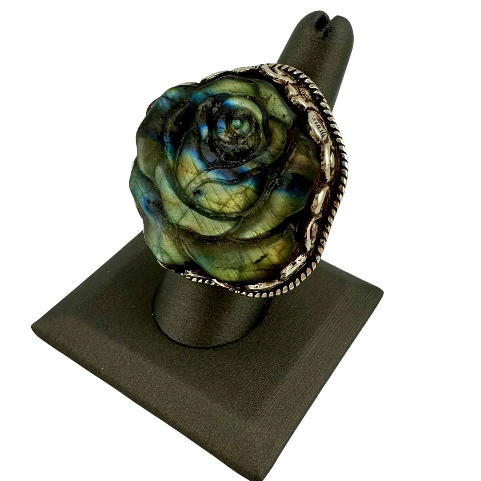 Rose-shaped green stone ring with silver band on a black stand
