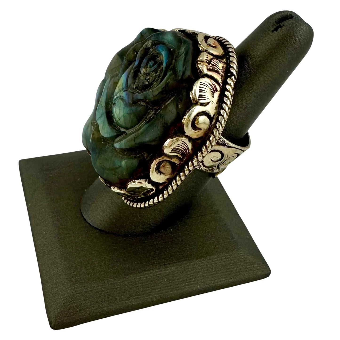 Decorative ring with floral design on a black stand against a white background
