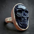 Skull-shaped sterling silver ring with dark indigo stone on a dark background