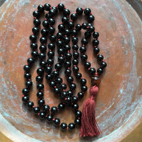 black tourmaline mala on textured brass background
