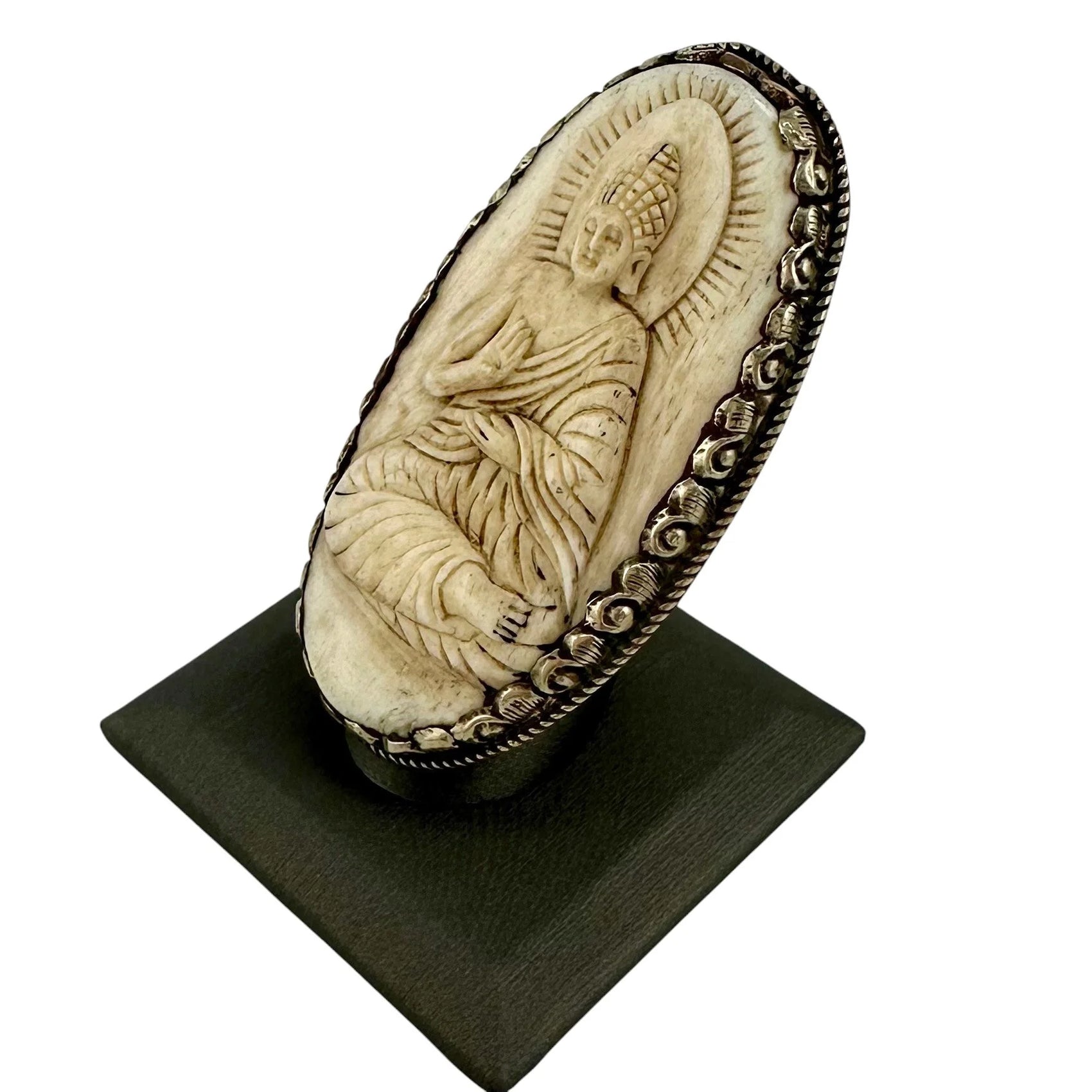 Carved bone plaque with a seated Buddha figure in a meditative pose on a white background