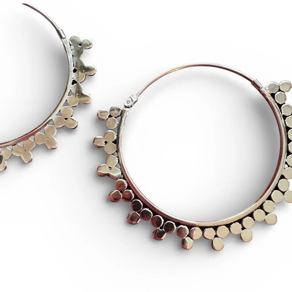 Pair of Indonesian silver hoop tribal earrings with a textured design on a white background