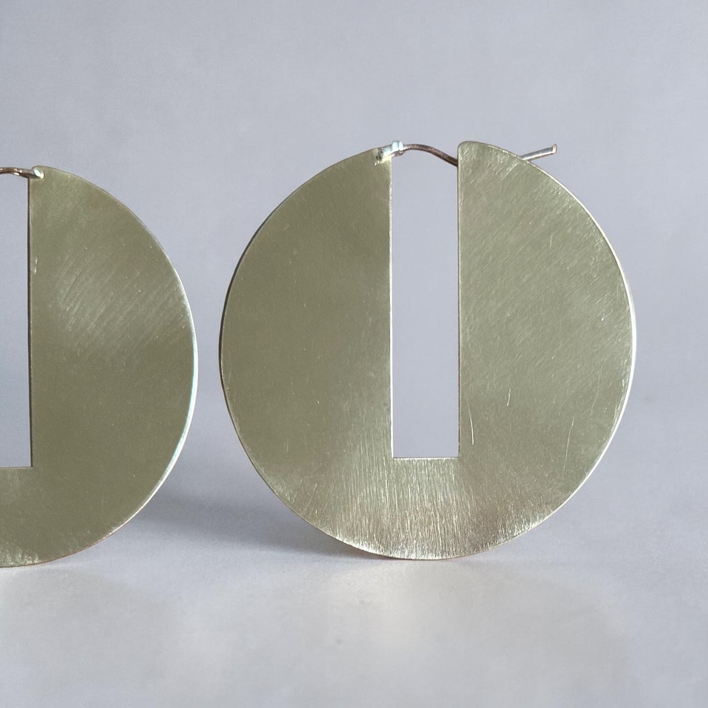 geometric brass hoop earring on a light blue background