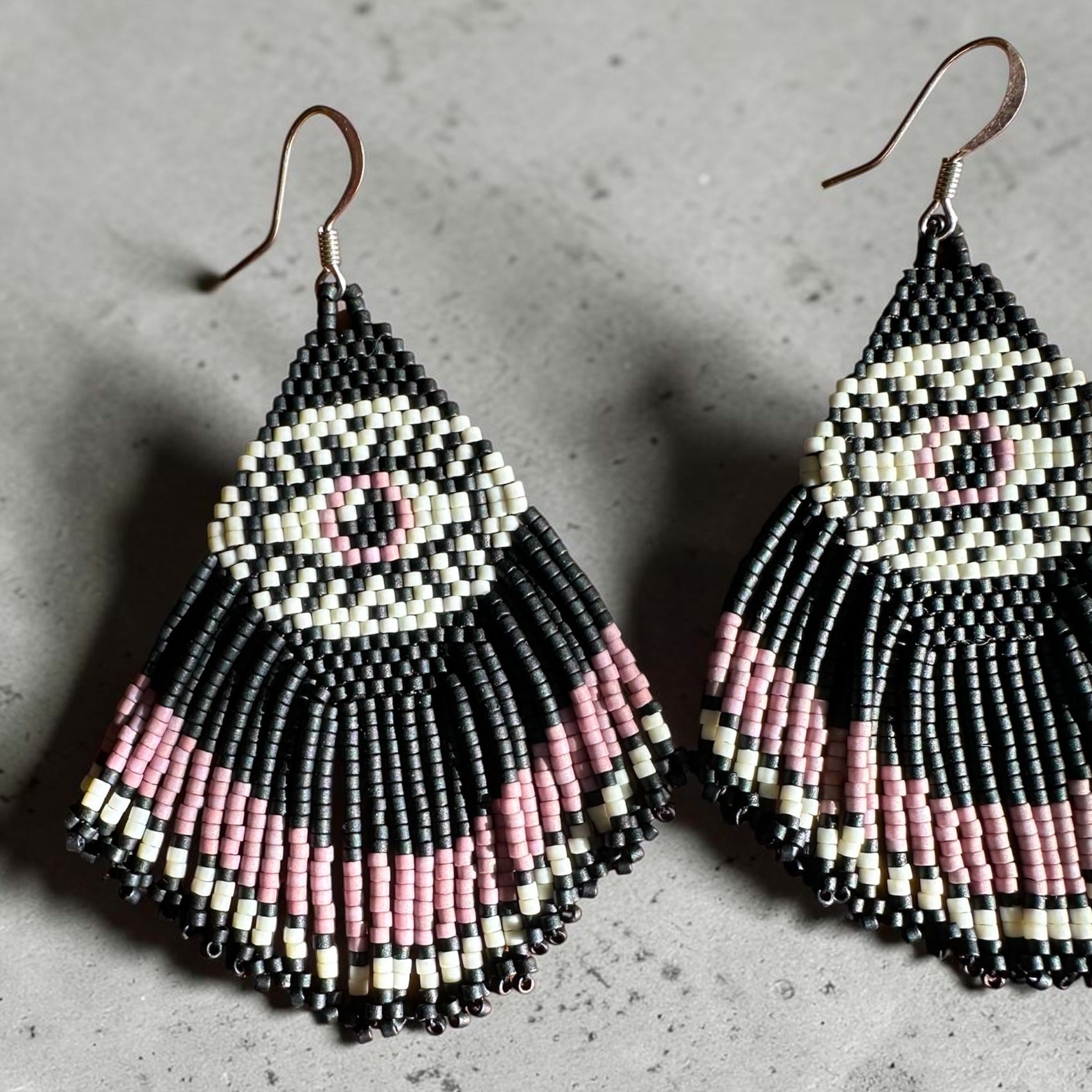 Pair of beaded earrings with mystic eye pattern on a gray surface