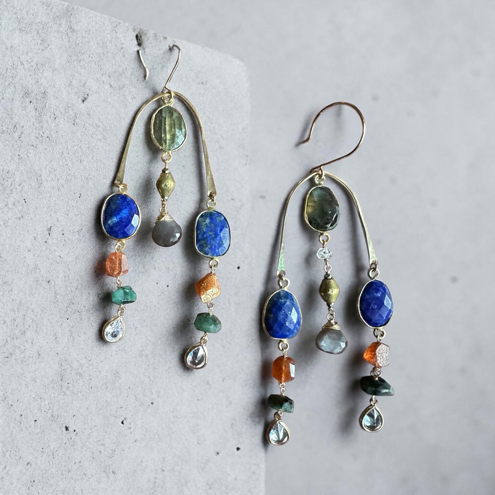 Multicolored semi-precious stone beaded handmade brass earrings on a textured gray surface