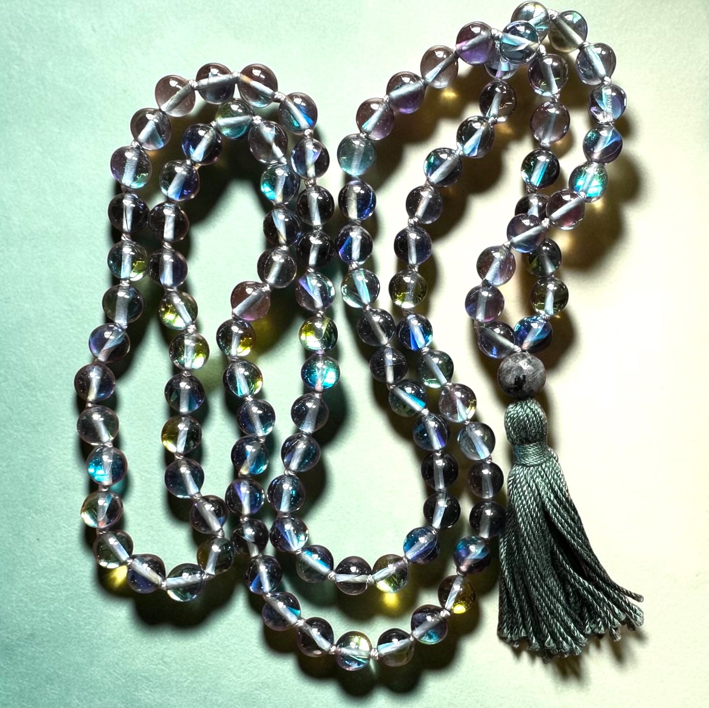 Crystal beaded necklace with a tassel on a light green background