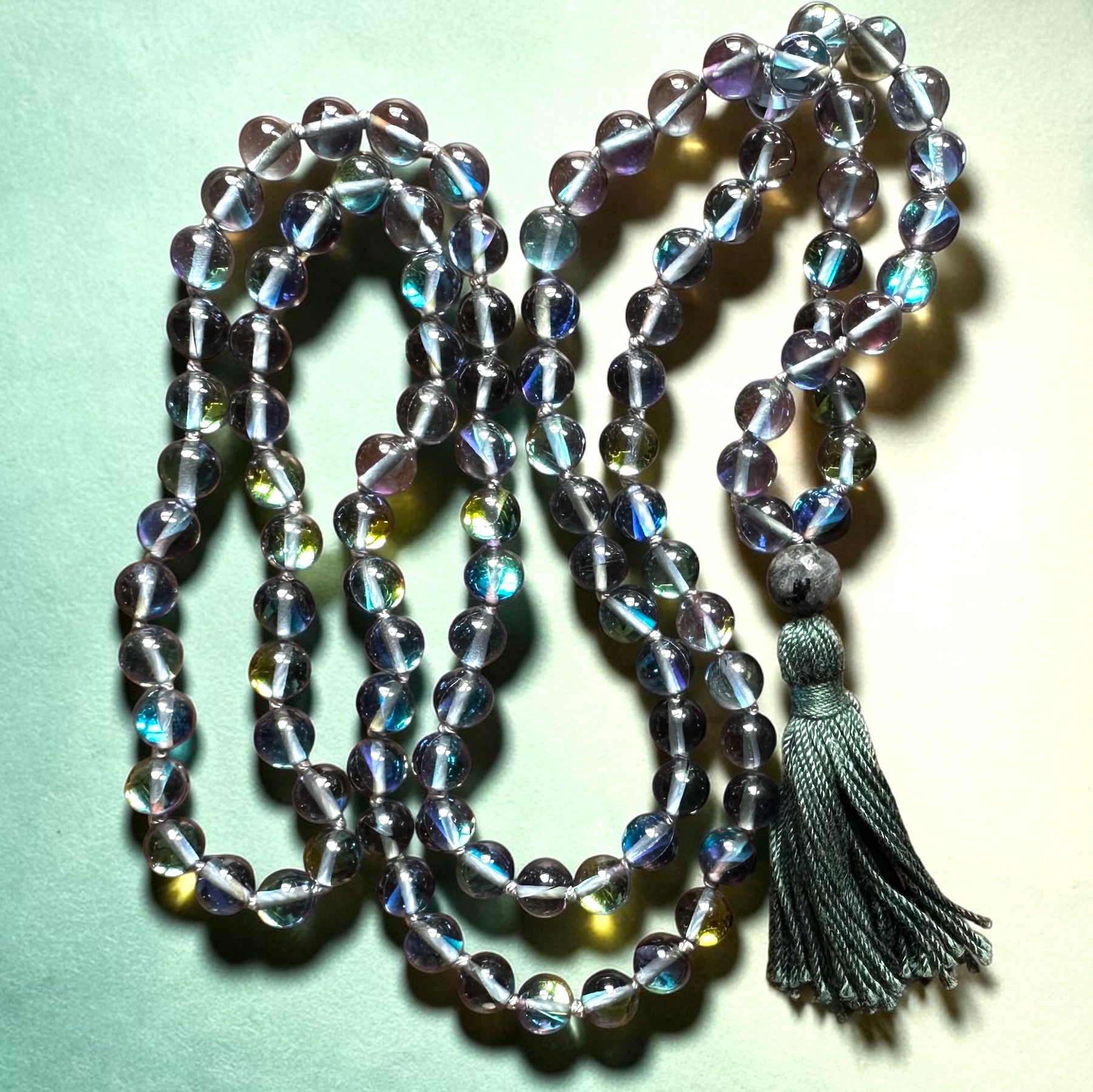 Crystal beaded necklace with a tassel on a light green background