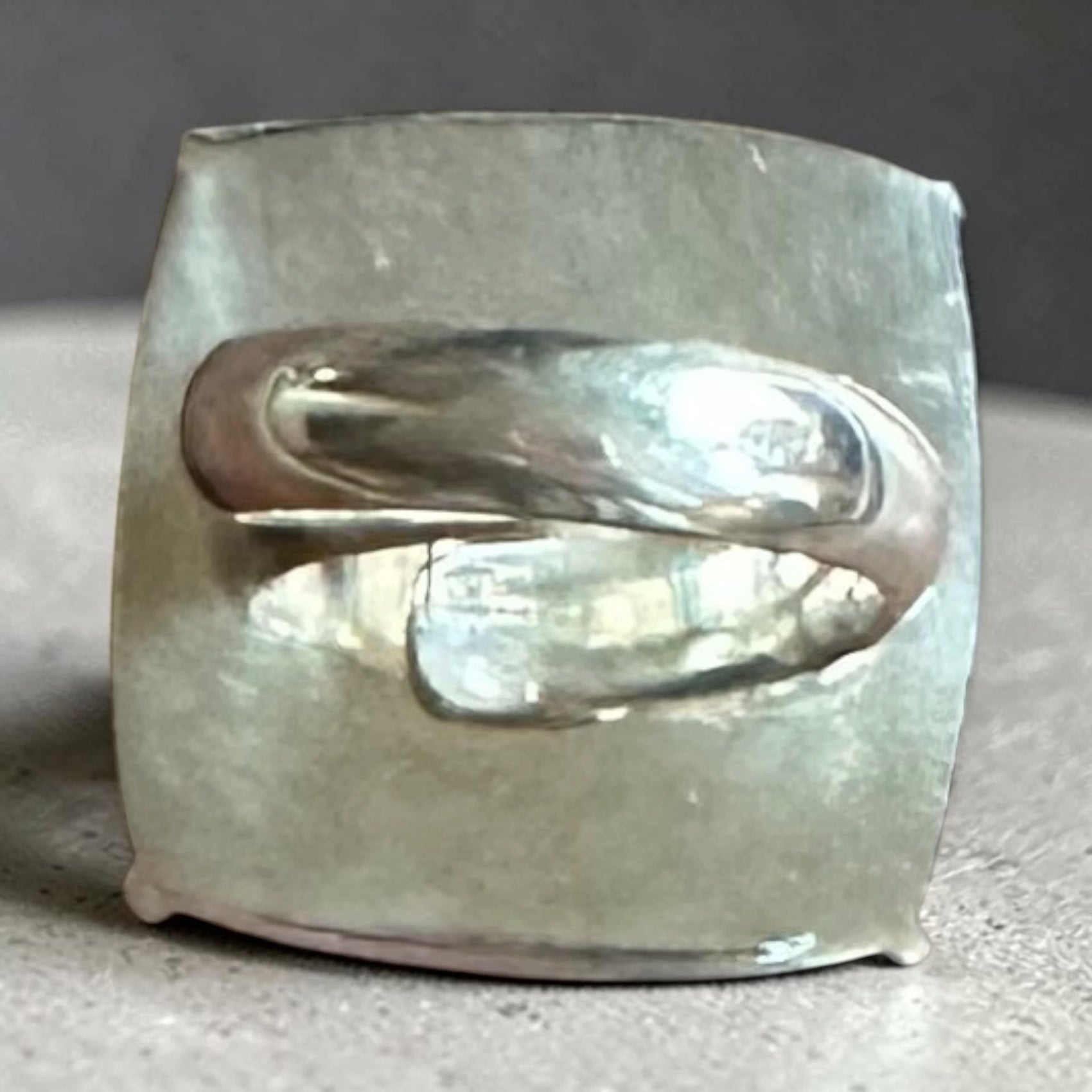 Silver ring with a textured band on a gray background