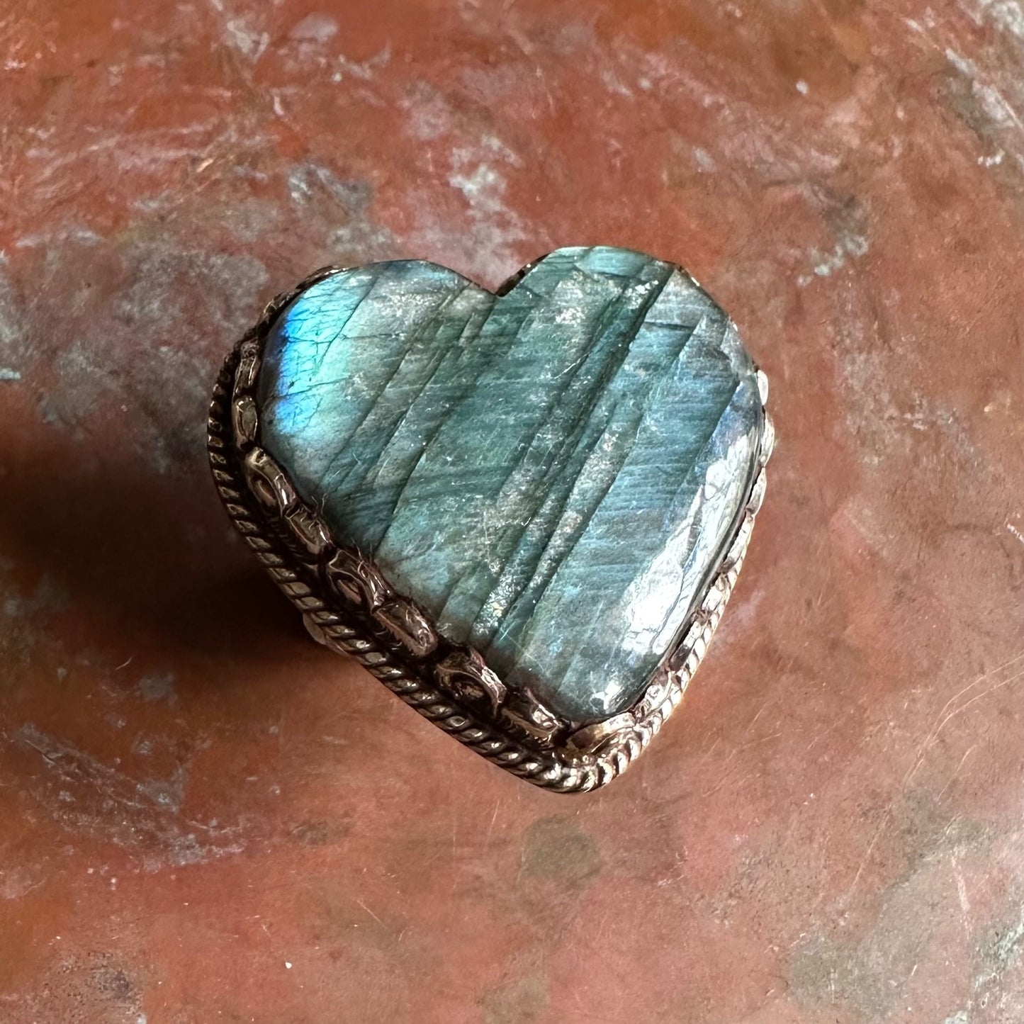 Heart-shaped stone with metallic frame on a textured surface
