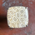 Square-shaped stone with coral pattern on a brown background