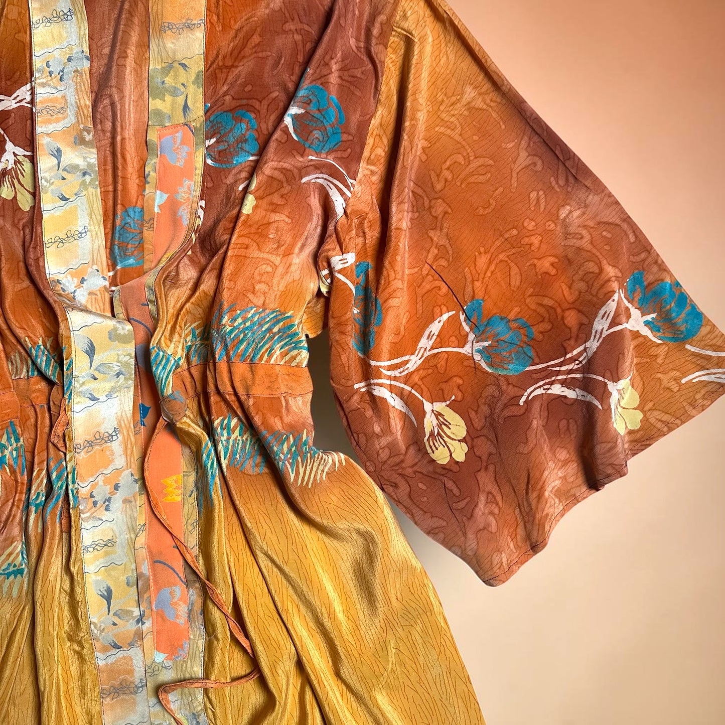 Textured kimono sleeve fabric with floral patterns in orange, blue, and white on a beige background