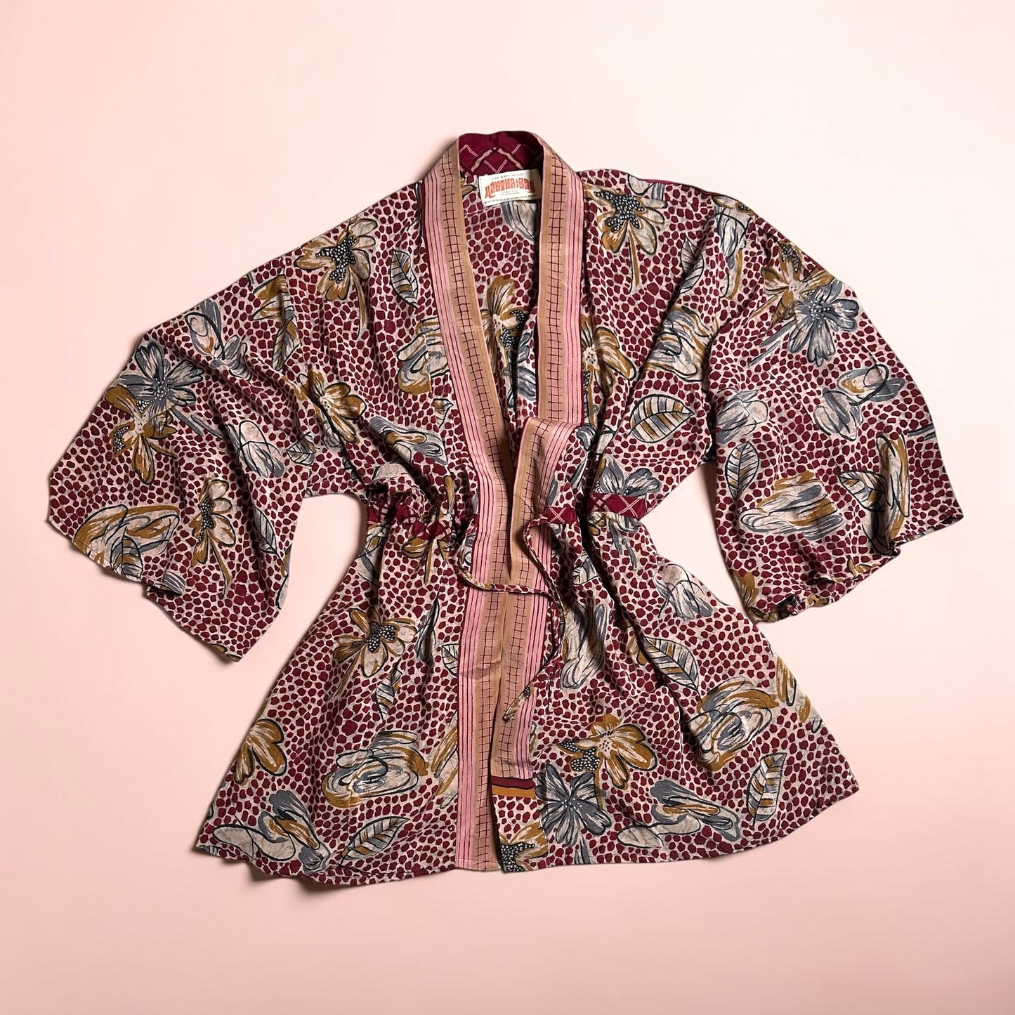 Floral-patterned kimono with a burgundy belt on a light pink background