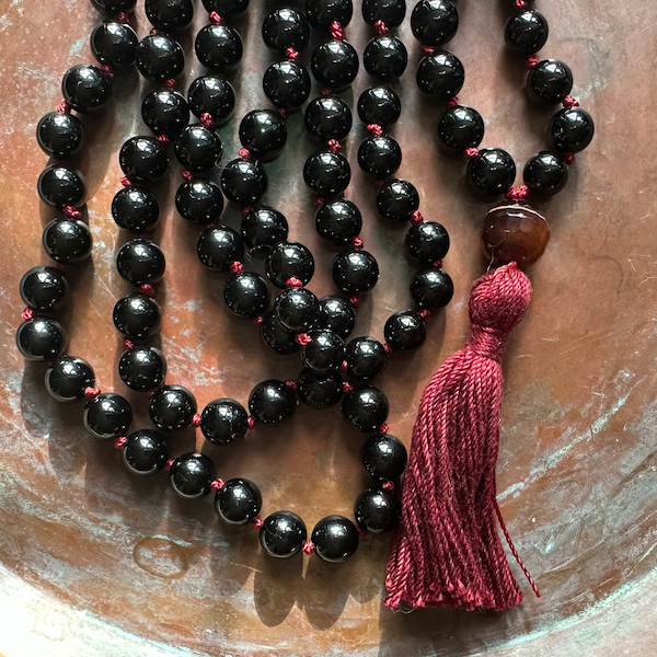 black tourmaline mala on textured brass background
