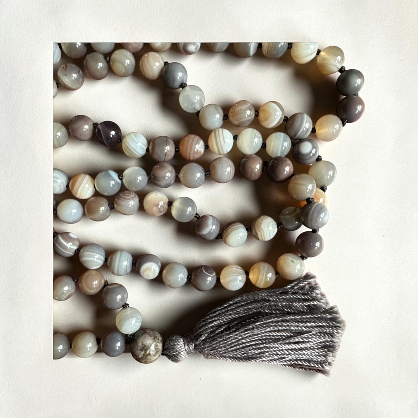 Necklace with multicolored agate beads and a tassel on a light background