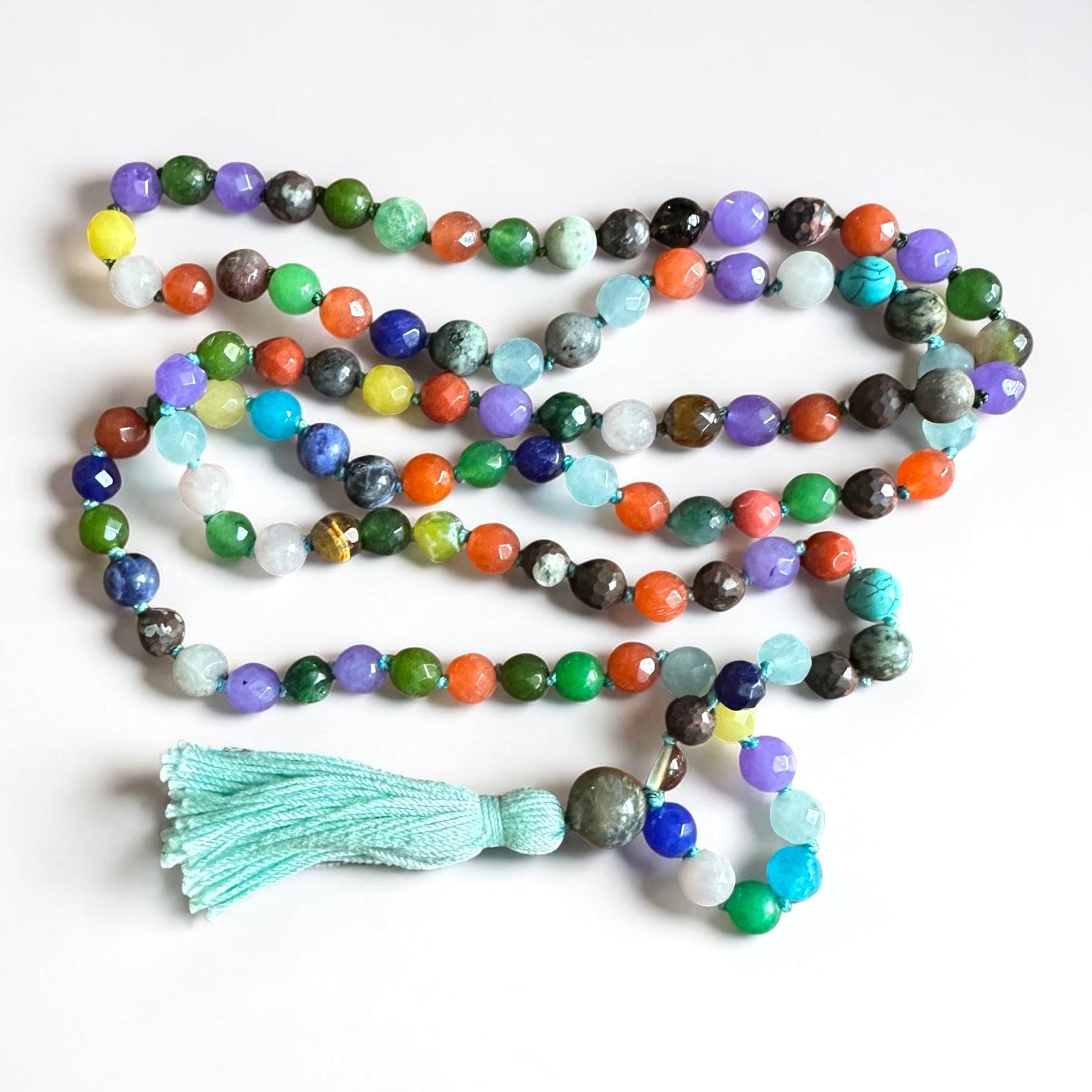 Colorful beaded agate mala necklace with aqua tassel on a white background