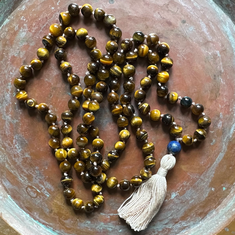 Handmade tigers eye mala necklace Tibetan prayer meditation beads on a weathered brass background 