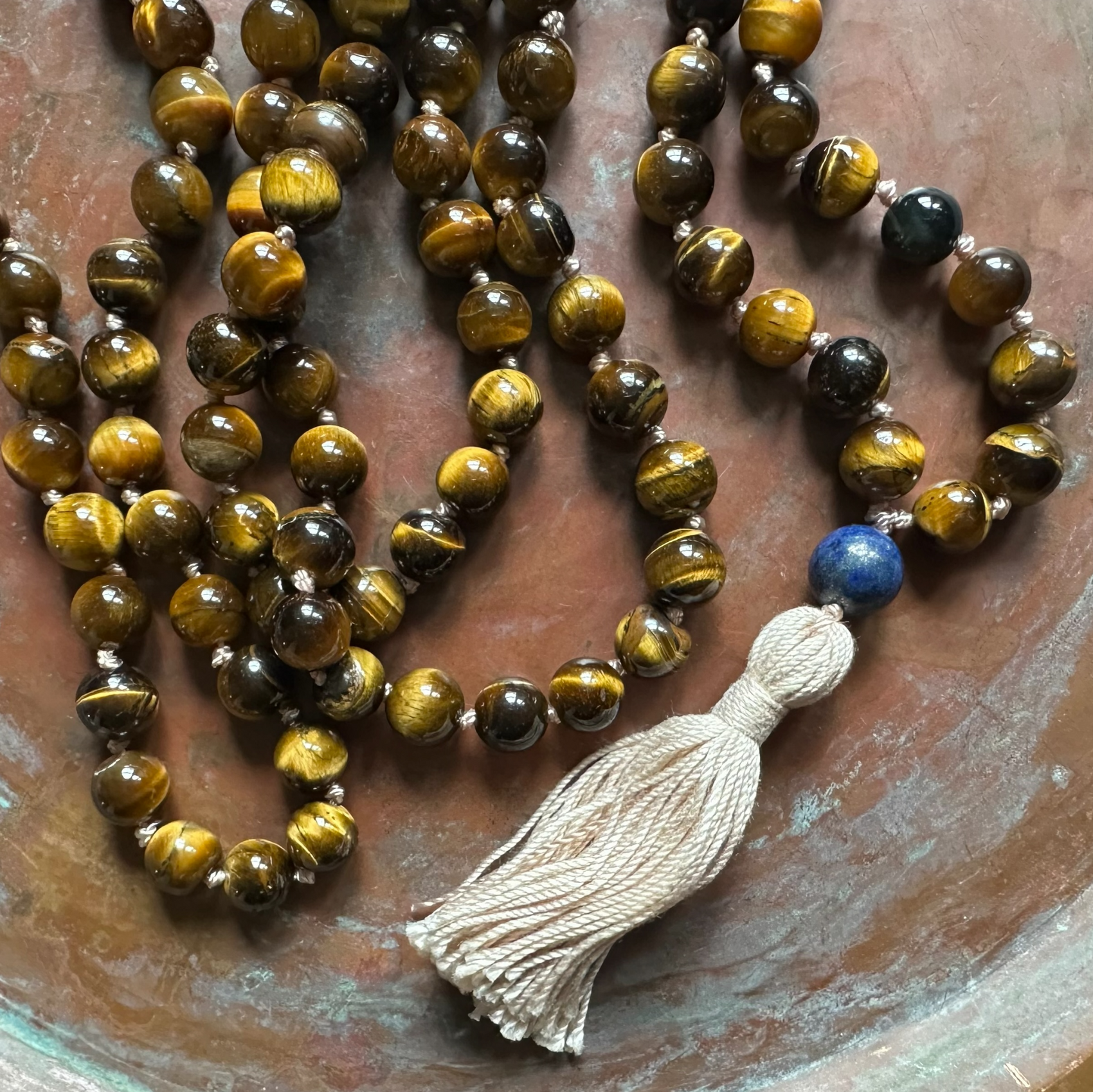 Handmade tigers eye mala necklace Tibetan prayer beads on a weathered brass background 