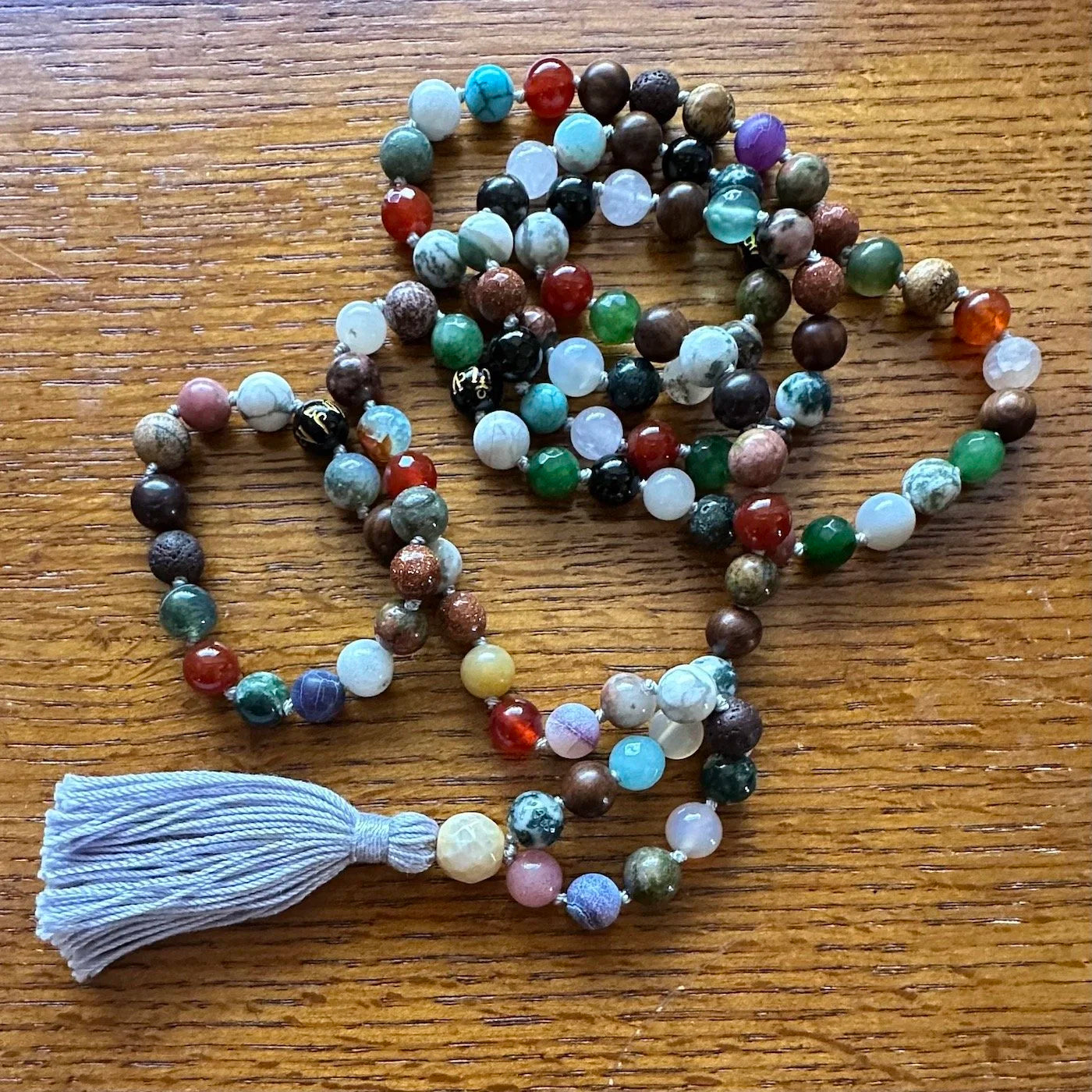 Multicolored beaded mala necklace with a tassel on a wooden surface