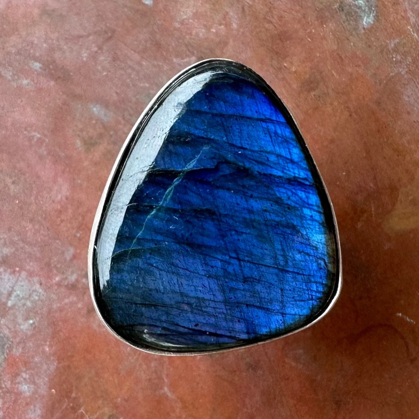 Blue labradorite stone in a silver setting on a brown surface