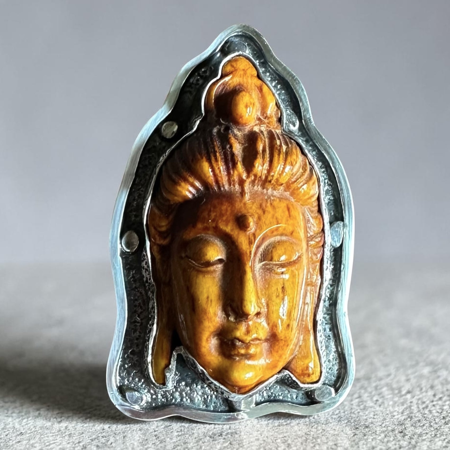 Sterling Silver Ring with carved Thai Buddha head design on a dark textured background