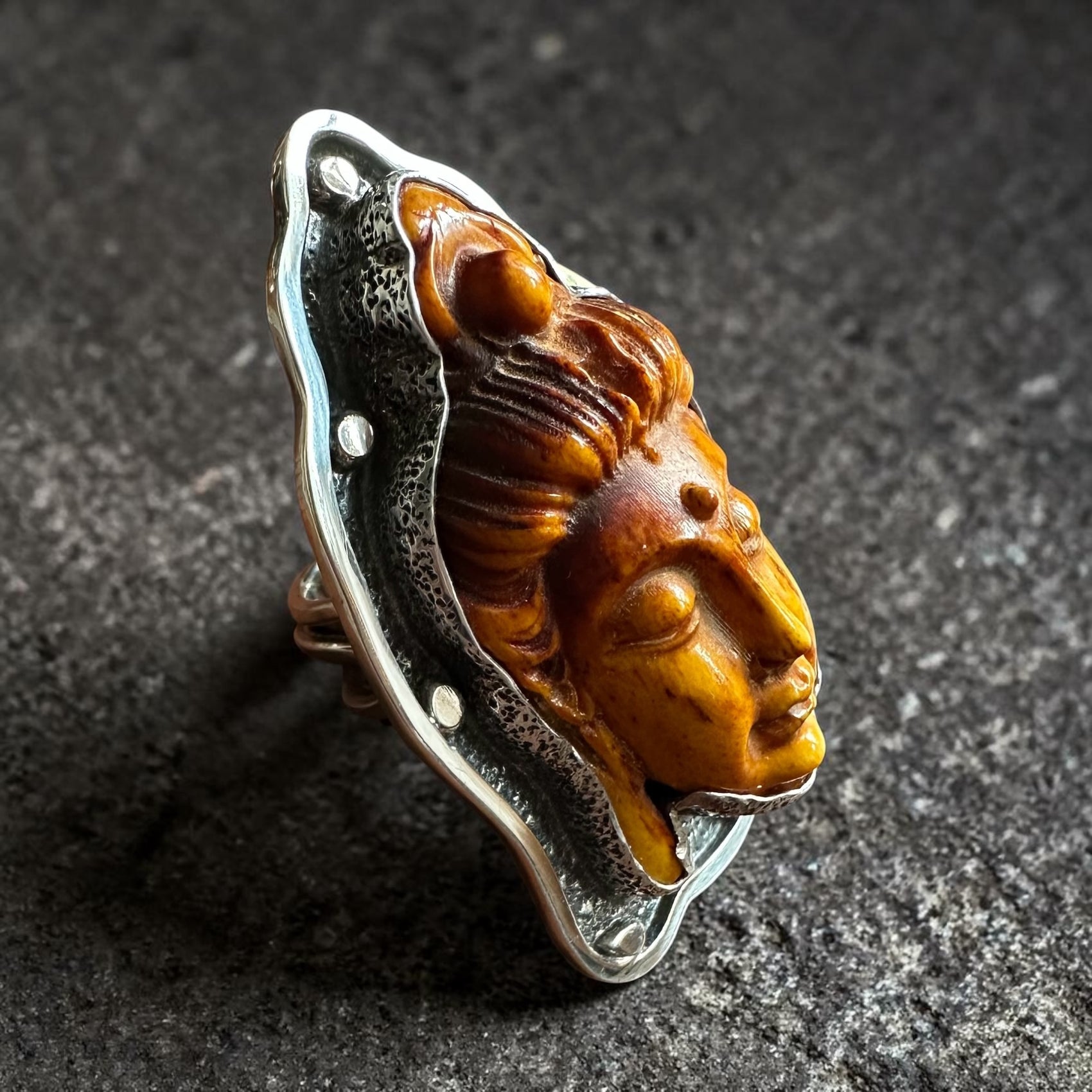 Sterling Silver Ring with carved Thai Buddha head design on a dark textured background