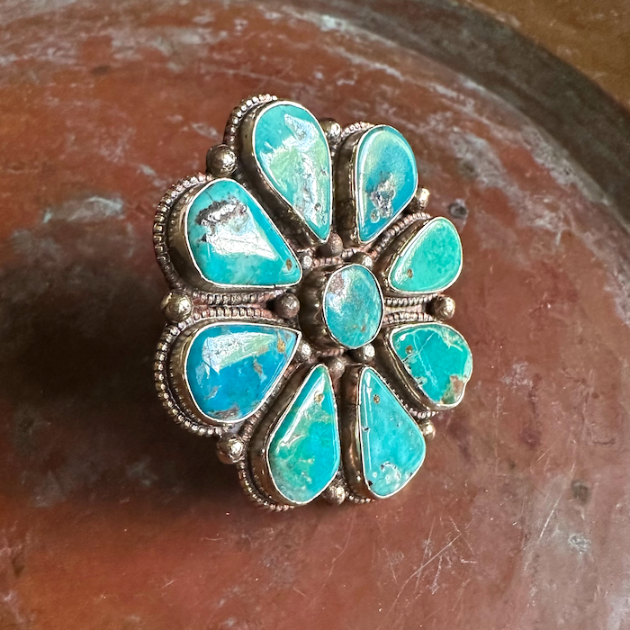Turquoise ring with floral silver setting on a brown surface