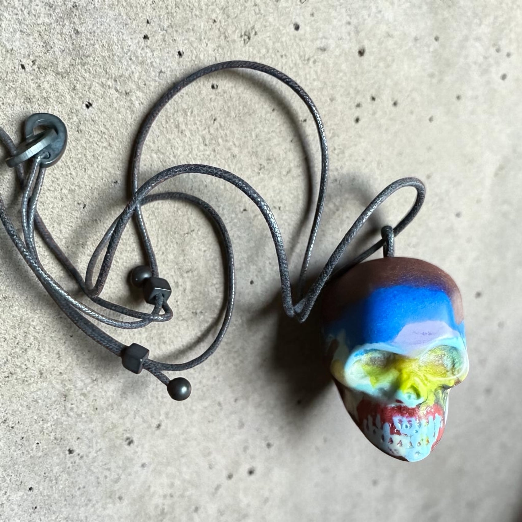 Necklace with a colorful skull pendant on a textured surface