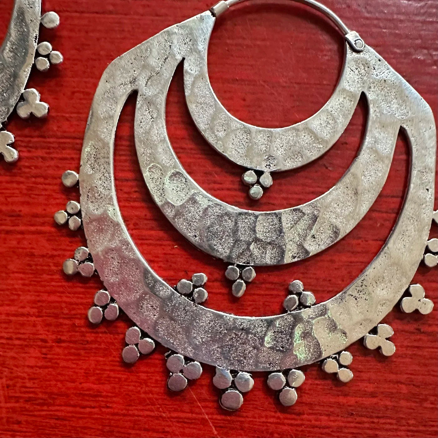 Indonesian Silver Tribal hoop earrings with dangling beads on a red surface