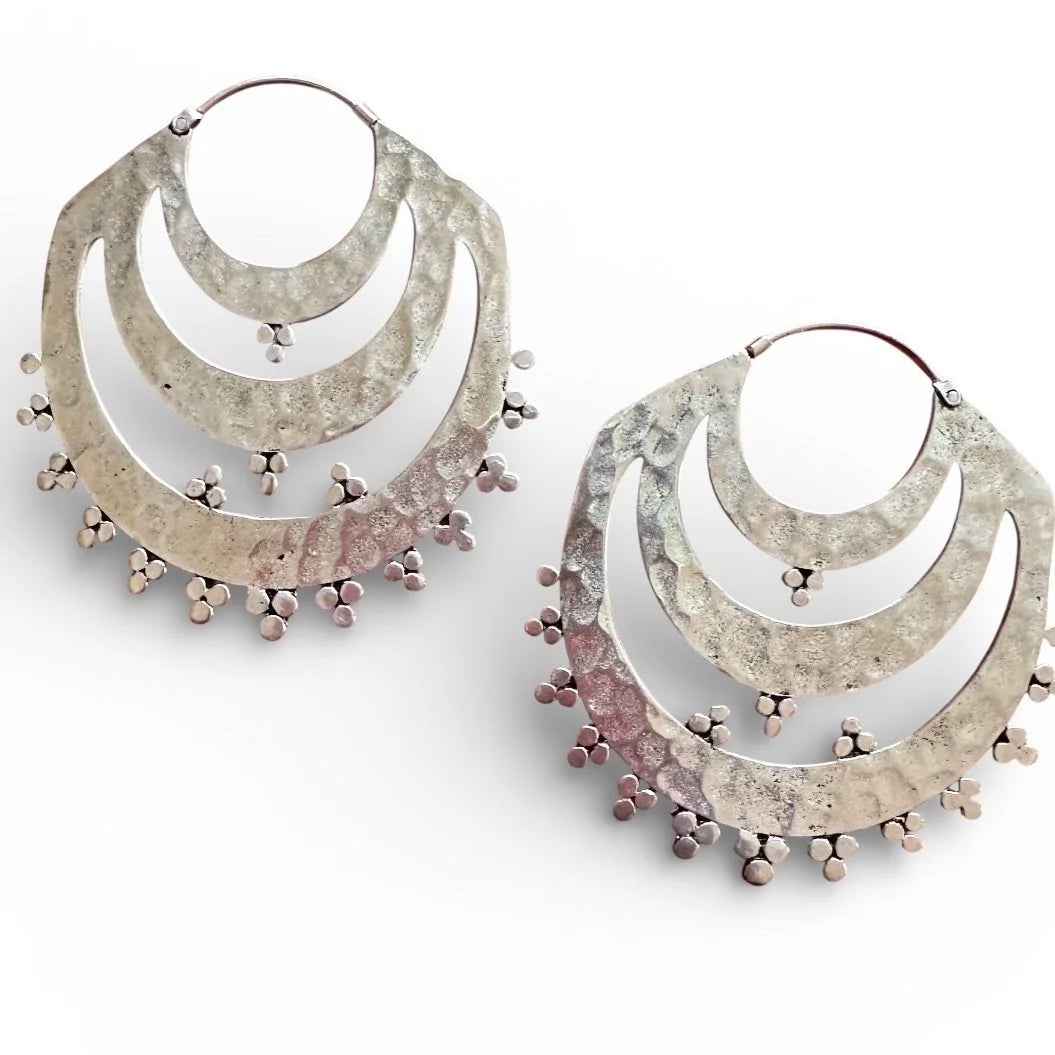 Pair of Indonesian silver tribal hoop earrings with star-like embellishments on a white background